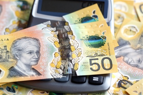 Two Australian fifty dollar notes on top of a calculator