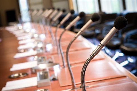 A series of desk microphones at a table in preparation for a council meeting