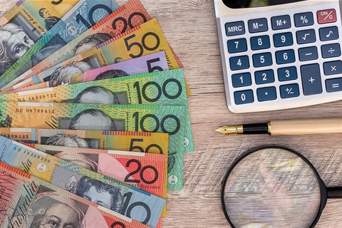 Australian bank notes next to a calculator, pen and magnifying glass