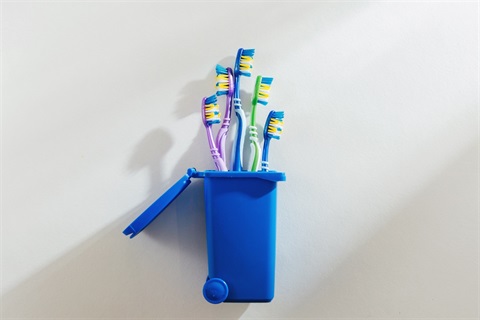 Toothbrushes sitting in a miniature recycling bin